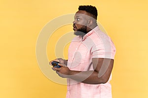 Man holding in hands gamepad joystick playing video games with big eyes and amazed facial expression