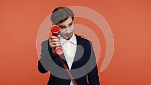 Man holding handset and pointing to camera