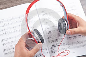 Man holding headphones on book of music note