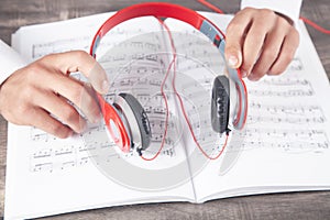 Man holding headphones on book of music note