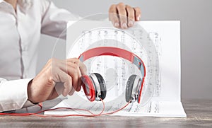 Man holding headphones on book of music note