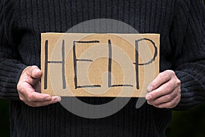 Man holding help homemade sign with dark background