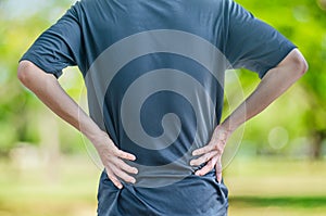 man holding his back in pain, monochrome photo with red as a symbol for the hardening