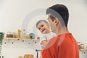 man holding his cute son in the living room, medium closeup family concept indoor