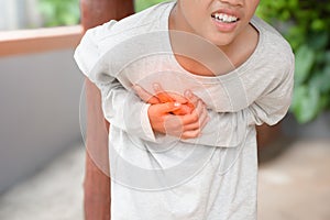 Man is holding his hand on his chest and has a painful expression due to heart disease symptoms on outdoor blurred background