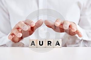 Man holding his hands protectively over the wooden cubes with the word aura