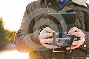 Man holding in his hands remote controller joystick transmitter flying the drone with sun shining bright day outdoors