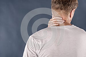Man holding his neck in pain on blue background. Lower neck pain. Shirtless man touching his neck for the pain