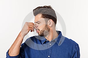 Man holding his nose against a bad smell isolated over grey background.