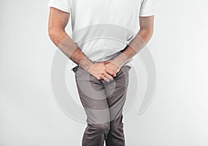 A man holding his penis with on the white background. Wants to go to the toilet.