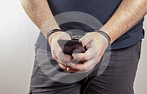 A man holding his phone in handcuffs on a white background,selective focus.Concept: the slave of technology, the right to one call