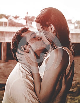 Man holding his wife and giving her a kiss on a warm red tone ph