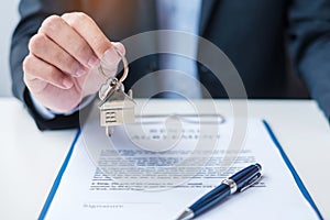Man holding home key during signing home contract documents. Contract agreement, real estate,  buy and sale and insurance concepts