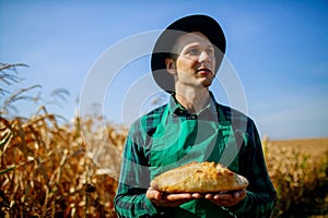 Man Holding Homemade Rustic Wheat Bread In Hands In A Wheat Field.