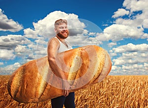 Man holding a huge bread on field of wheat