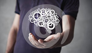 Man holding human brain from gears and cogs mechanism