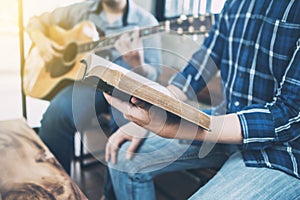 a man holding hymn books and sing a song while his friend playing guitar