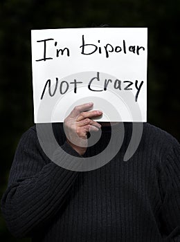 Man holding I`m bipolar not crazy homemade sign with dark background photo