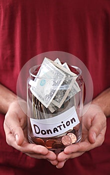 Man holding jar with money and label DONATION