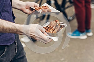 man holding juicy steak grilled meat in take to go box at street