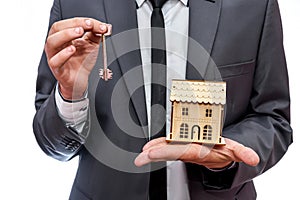 Man holding key and wooden house model close up