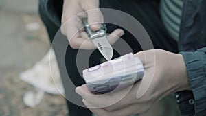 A man holding a knife and money. Preparing the attempt on the life of. Doubt and conscience. Close-up money