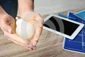 Man holding lamp bulb over table