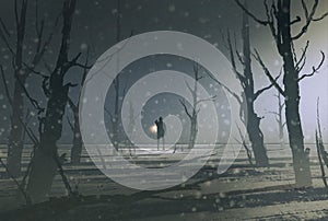 Man holding lantern stands in dark forest with fog photo