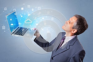 Man holding laptop with cloud based system notifications