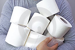 A man is holding a large amount of toilet paper