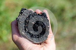 Man holding a large piece of black asphalt in hand, object closeup, detail, macro shot. Asphalt material simple concept, road