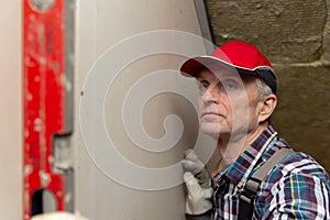 Man holding level against interior drywall. Attic insulation and renovation