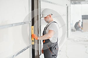 Man holding level against plasterboard, interior drywall. Attic renovation