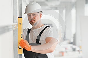 Man holding level against plasterboard, interior drywall. Attic renovation