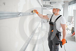 Man holding level against plasterboard, interior drywall. Attic renovation