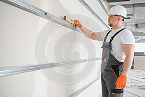 Man holding level against plasterboard, interior drywall. Attic renovation