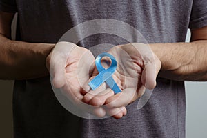 Man holding light blue ribbon. Awareness ribbon