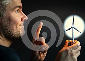 Man holding a light bulb with a wind turbine inside.