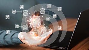 Man holding a light bulb while working on a laptop to think and create new ideas. Ai technology, cloud computing, technology photo