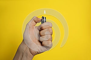 Man holding lighter on yellow background, closeup. Space for text