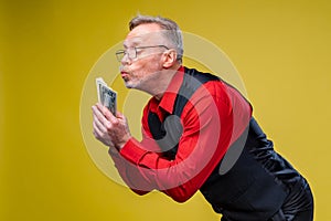 Man holding lots of dollar bills in hands, isolated on yellow background