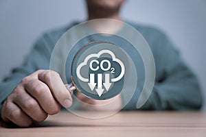 Man holding magnifier glass with CO2 reducing for decrease CO2 , carbon footprint and carbon credit to limit global warming from