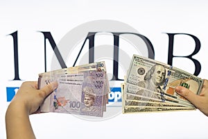 Man holding Malaysia Ringgit with burr 1MDB background indicating the US Government inves