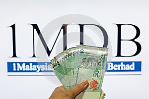 Man holding Malaysia Ringgit with burr 1MDB background indicating the US Government inves