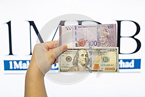 Man holding Malaysia Ringgit with burr 1MDB background indicating the US Government