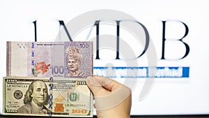 Man holding Malaysia Ringgit with burr 1MDB background indicating the US Government