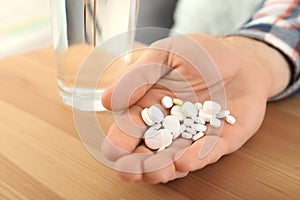 Man holding many pills in hand at table