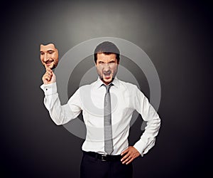 Man holding mask with smiley face