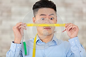 man holding measuring tape in front face