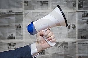 A man holding a megaphone on background of newspapers. News message concept. Concept for news and information